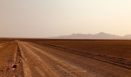 Scenic view of dirt road against clear sky