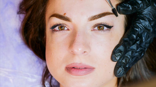 Cropped hands of beautician coloring woman eyebrow