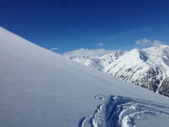 Scenic view of snowcapped mountains against blue sky