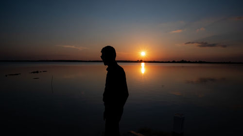 Silhouette man standing at beach during sunset