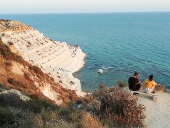 People looking at sea against sky