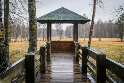 Wooden built structure by bare trees against sky