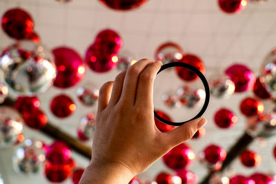 Cropped image of woman holding bangle against ceiling