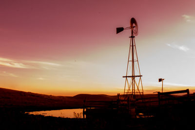 Silhouette cranes against sky during sunset