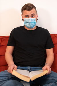 Portrait of man sitting on book at home