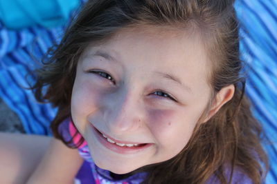 High angle portrait of girl smiling while sitting on picnic blanket