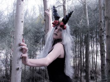 Woman standing by tree in forest