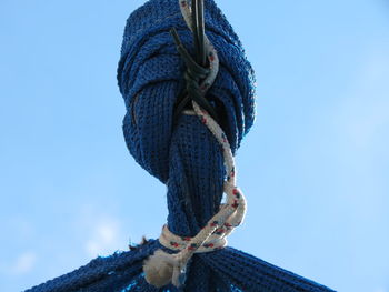 Low angle view of rope tied up against blue sky