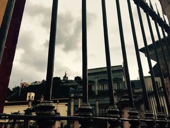 View of buildings against cloudy sky seen through glass window