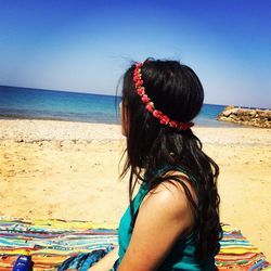 Rear view of woman at beach against sky