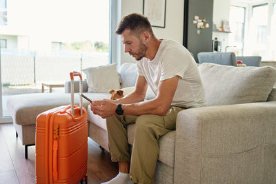 Side view of woman using mobile phone while sitting on sofa at home