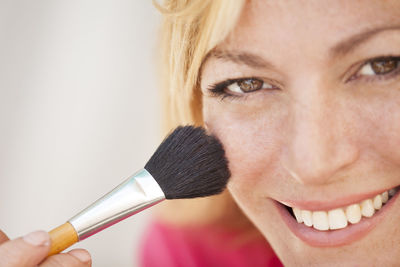 Close-up portrait of woman applying make-up