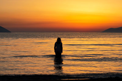 Silhouette man looking at sea against sky during sunset
