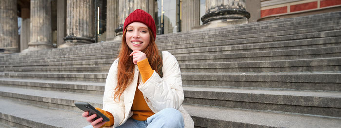 Young woman standing against wall