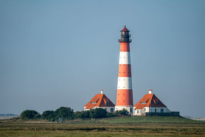 Lighthouse by sea against clear sky