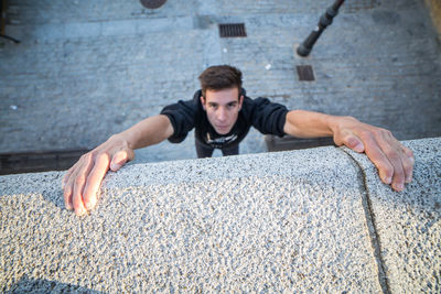 Portrait of young man climbing on concrete wall