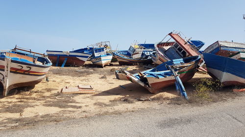 Boats moored on beach against clear blue sky