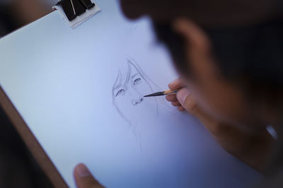 Close-up of person making sketch on paper