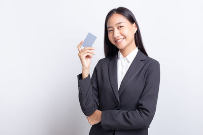 Portrait of a smiling young woman standing against white background