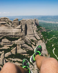 Low section of person on rock against sky