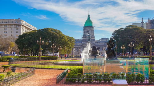 Fountain in city against sky