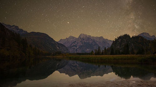 Reflection of mountains in lake against sky at night