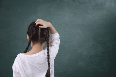 Rear view of girl standing by blackboard