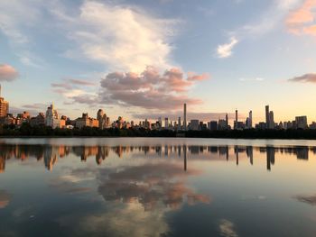 Reflection of buildings in lake against sky during sunset