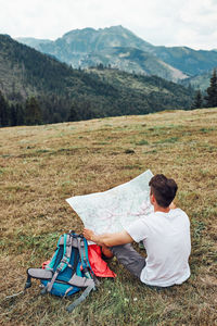 Rear view of man sitting on field