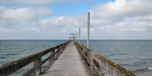 Wooden pier over sea against sky