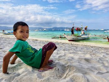 Portrait of boy sitting on beach against sky