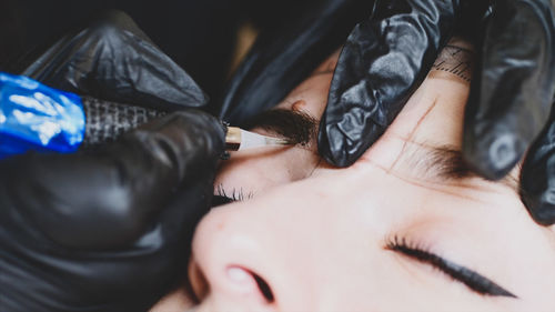 Cropped hands of beautician coloring woman eyebrow