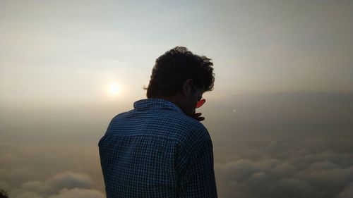 Rear view of man wearing sunglasses against sky during sunset