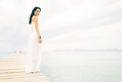 Woman standing by sea against sky