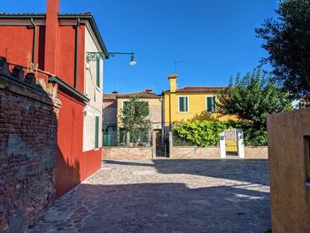 Alley amidst buildings against blue sky