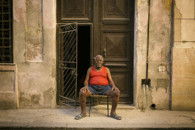 Portrait of man sitting on seat against building