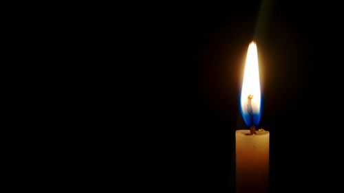 Close-up of lit candle in darkroom