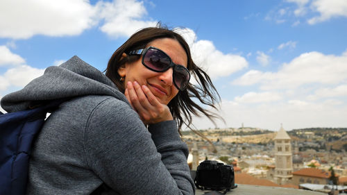 Portrait of young woman wearing sunglasses sitting against sky