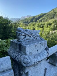 Stone wall against trees and mountains against clear sky
