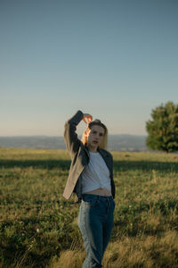 Portrait of a young woman standing in a field during sunset