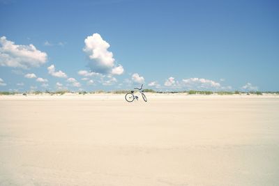 Bicycle parked at beach against sky