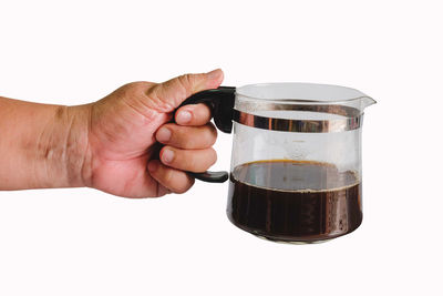 Close-up of hand holding coffee cup against white background