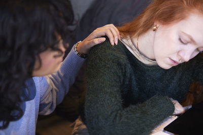 Female friends sitting together where one comforts the other who is depressed