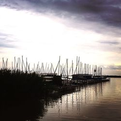 Silhouette boats moored at harbor against sky