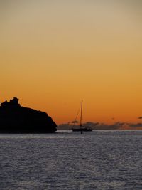 Silhouette sailboats in sea against sky during sunset