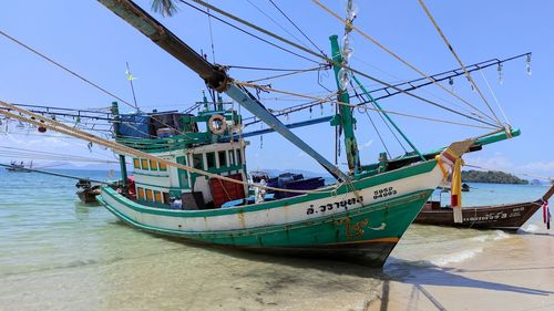 Fishing boats moored on beach against clear sky