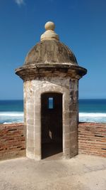 Built structure on beach by sea against clear blue sky