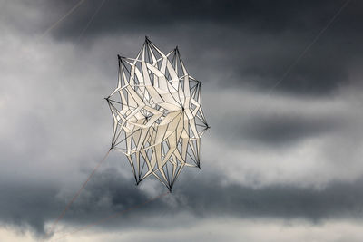 Star shape kite with strings flying in sky