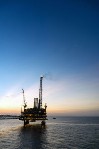 Silhouette of oil production platform during sunset at offshore oil field