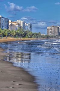 Scenic view of sea by buildings against sky